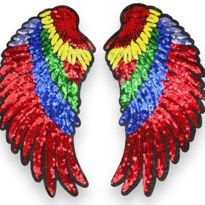 Puede incluir: Un par de alas de ángel de lentejuelas multicolores con lentejuelas rojas, amarillas, verdes, azules y moradas. Las alas son perfectas para añadir un toque de brillo a cualquier atuendo.
