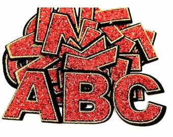 May include: A pile of red glitter alphabet letters with black borders and gold trim. The letters are in various sizes and orientations, against a white background. Ideal for craft projects and customisation.