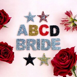 May include: Silver, gold, red, and black glitter letters spelling "ABCD BRIDE" with two silver glitter stars and two red glitter stars on a pink background.
