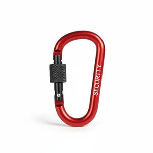 May include: A red carabiner with a black screw-gate locking mechanism. The word SECURITY is printed in white capital letters along the side of the metal frame. The device features a spring-loaded gate and a textured, cylindrical locking nut.