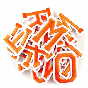 Puede incluir: Un montón de letras de fieltro naranja con contornos blancos. Las letras son de varios tamaños e incluyen las letras L, M, O y X.