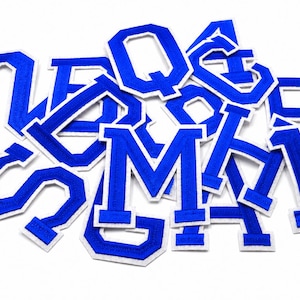 Könnte beinhalten: Eine Ansammlung blauer, gestickter Varsity-Buchstabenaufnäher mit weißen Rändern. Die Buchstaben sind in einem kräftigen Blockstil gehalten und auf einem weißen Hintergrund verstreut. Diese Aufnäher sind ideal zum Anpassen von Kleidung.