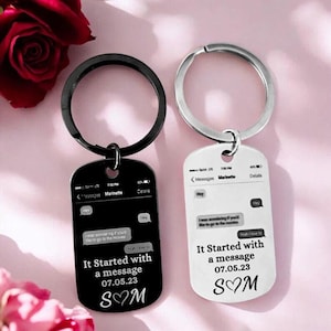 May include: Two keyrings with a dog tag design. One is black, the other white. Both have a phone message design with the text "It Started with a message 07.05.23 S♡M". The keyrings have a silver and black ring.