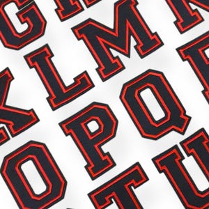 May include: Black and red felt letters of the alphabet, with a white background. The letters are in a bold, blocky font.