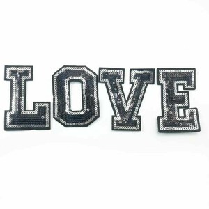 Peut inclure: Patch thermocollant en sequins noirs et argent&eacute;s qui &eacute;pelle le mot "LOVE" en grandes lettres majuscules.