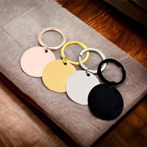 May include: Four round metal keychains with blank circular tags in rose gold, gold, silver, and black.