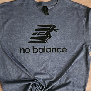 May include: A blue t-shirt with a black graphic of a person running on a set of stairs. The text "no balance" is printed below the graphic.