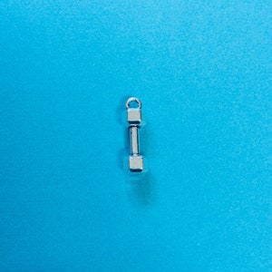 May include: A silver dumbbell charm on a blue background.