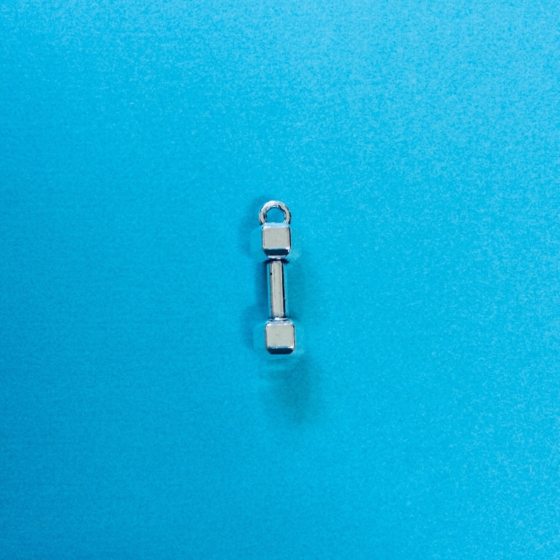 May include: A silver dumbbell charm on a blue background.