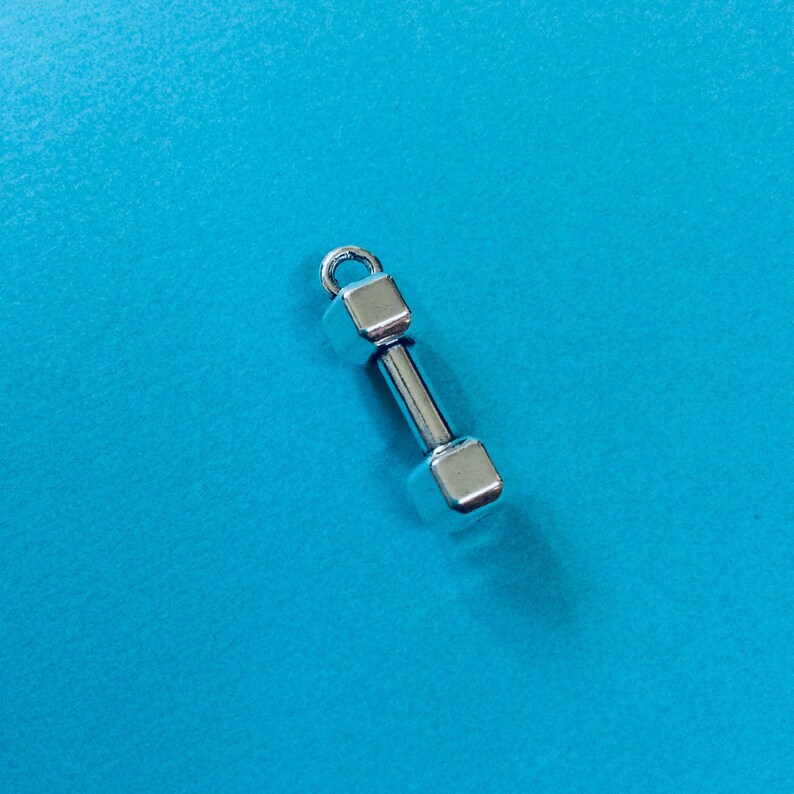 May include: A silver dumbbell charm with a square shape on each end.