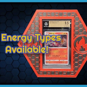 May include: A red and black hexagonal display case with a clear plastic insert holding a Pokemon trading card. The card is a Charmeleon from the Dragon Storm set and is graded 9.5 by Beckett Grading Services. The text on the card reads "リザード" and "80". The case has a red and black flame design on the side. The text "11 Energy Types Available!" is written in yellow on a blue background.
