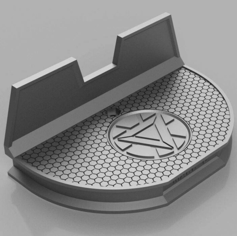 May include: A gray 3D printed phone stand with a honeycomb pattern and a circular Iron Man logo in the center. The stand has a raised back to hold a phone upright.
