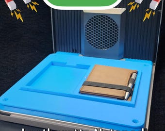 May include: A blue leatherette notepad with a brown leatherette cover and a pen. The notepad is sitting on a gray surface with a black speaker in the background. The text "F1 ULTRA" is visible in green letters above the speaker. The text "Leatherette Notepad" is visible below the notepad.