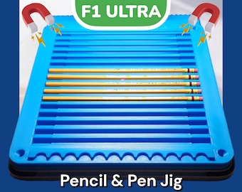 May include: A blue plastic jig with the text "F1 ULTRA Pencil & Pen Jig" on the bottom. The jig has multiple slots for holding pencils or pens in place.