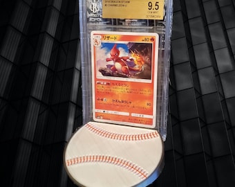 May include: A graded Pokemon card featuring Charmeleon from the Dragon Storm set. The card is in a protective case and is rated 9.5 Gem Mint. The card is displayed on a baseball-themed stand.