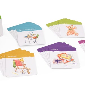 K&ouml;nnte beinhalten: Ein Satz bunter Karten mit Illustrationen und Text. Die Karten sind in Stapeln mit verschiedenen farbigen R&auml;ndern angeordnet. Der Text auf den Karten lautet "Summer", "Spare room/office", "Keep it", "Read it" und "Frame it".