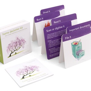 K&ouml;nnte beinhalten: Ein Home-Decluttering-Kit mit einer lila und gr&uuml;nen Box und Karten mit Illustrationen und Text, der "Verbrennen", "Schreddern", "Lesen", "Scannen oder digitalisieren", "Wichtige Dokumente" und "Ablegen" lautet.
