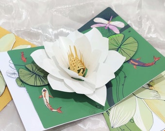 Puede incluir: Una tarjeta pop-up de flor de loto blanca con hojas verdes y peces. La tarjeta mide 12,7 cm por 17,8 cm y es perfecta para una ocasión especial.