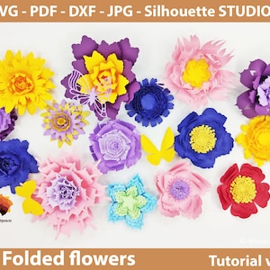 May include: A collection of folded paper flowers in various colors, including yellow, pink, purple, blue, and red. The flowers are arranged on a white surface. The text "Folded flowers" and "Tutorial video" is visible at the bottom of the image.