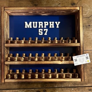 May include: A wooden baseball bat display shelf with three tiers. The shelf is painted blue and has a white sign with the name "MURPHY" and the number "57".