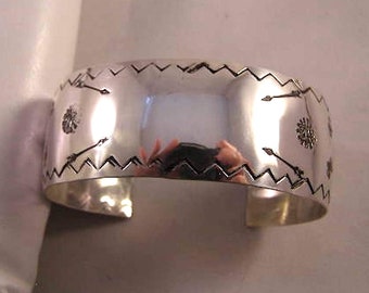 May include: A silver cuff bracelet with a geometric design of arrows and zigzags. The bracelet is polished and has a smooth finish.