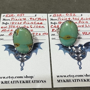 May include: Two turquoise rings with silver settings are displayed on cards with text. The rings have oval-shaped turquoise stones with brown veining. The cards have the Etsy shop URL and a dragon graphic.