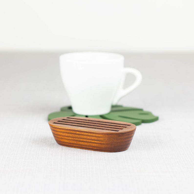 May include: A wooden coaster with a grooved design, perfect for holding a cup of coffee or tea. The coaster is brown and has a natural wood finish.