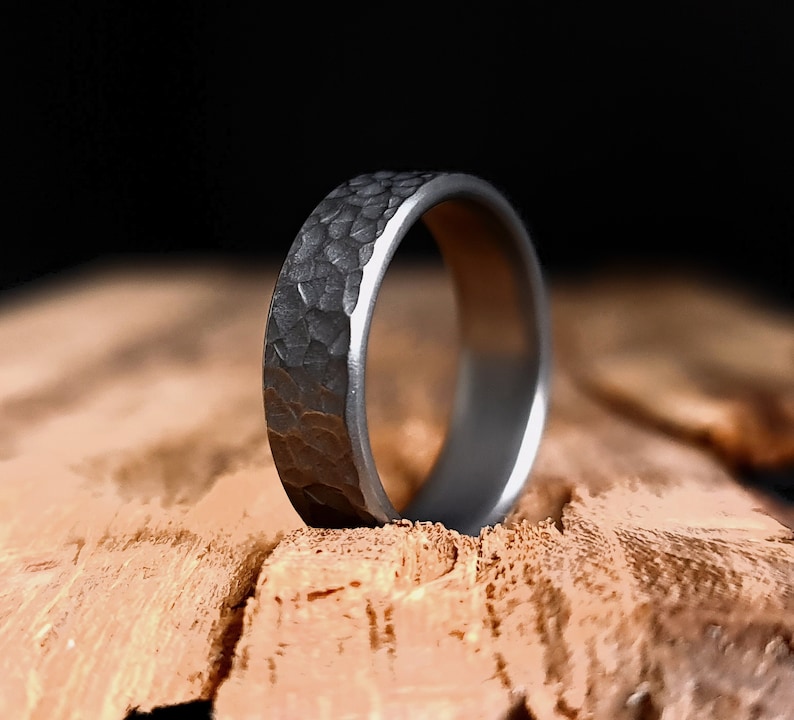 May include: A dark gray hammered metal ring with a textured surface.