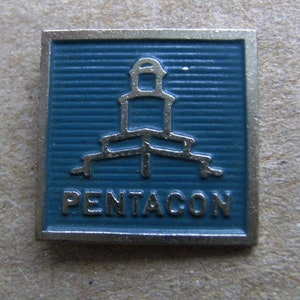 May include: A silver and blue enamel pin with a stylized image of the Pentagon building and the word "PENTACON" below it.