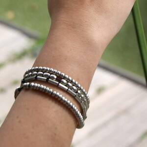 May include: A silver beaded bracelet with multiple strands. The bracelet is worn on a person's wrist.