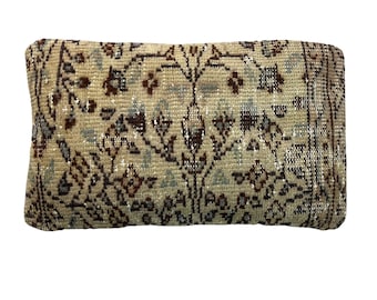 May include: A beige pillow with a floral pattern in shades of brown, red, and blue. The pillow is made of a soft, woven fabric and has a rectangular shape.
