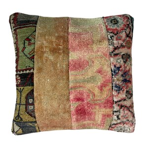 May include: A square throw pillow with a patchwork design. The pillow is made of four different pieces of fabric, each with a different pattern. The fabric is a mix of red, pink, green, blue, and brown. The pillow is perfect for adding a touch of bohemian style to any room.