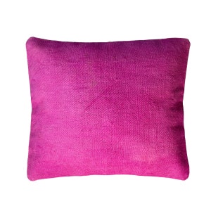 May include: A square decorative pillow in a vibrant fuchsia color. The pillow has a textured appearance, with visible woven threads. The pillow is a solid color and appears to be made of a soft fabric.