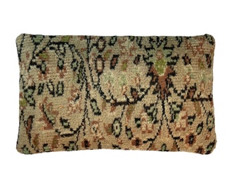 May include: A rectangular pillow with a beige background and a black, brown, and green floral pattern.