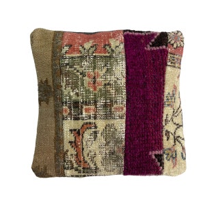 May include: A square pillow with a patchwork design. The pillow is made of different fabrics with various patterns, including floral and geometric designs. The colors are mostly muted, with shades of brown, green, pink, and purple.