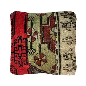 May include: A square pillow with a red, green, and white patterned fabric. The fabric has a traditional design with geometric shapes and floral motifs.