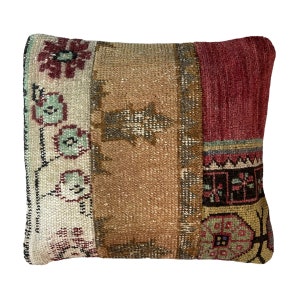 Può includere: Un cuscino quadrato con un design a patchwork. Il cuscino è realizzato con tessuti di diversi colori con motivi floreali e geometrici. I colori sono rosso, marrone, beige e verde.