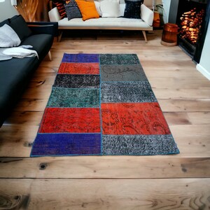 Puede incluir: Una alfombra de patchwork colorida con cuadrados rojos, azules, verdes y negros. La alfombra está hecha de materiales reciclados y tiene un aspecto único, tejido a mano.