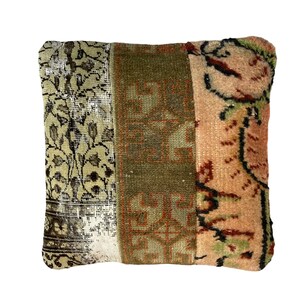 May include: A square throw pillow with a patchwork design. The pillow is made of three different fabrics, each with a different pattern. The fabric on the left side of the pillow is a light beige with a floral pattern. The fabric in the middle is a dark green with a geometric pattern. The fabric on the right side of the pillow is a light pink with a floral pattern.