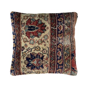 May include: A rectangular pillow with a colorful, intricate pattern. The pillow is made of a woven fabric with a distressed look. The pattern features shades of red, blue, and beige.