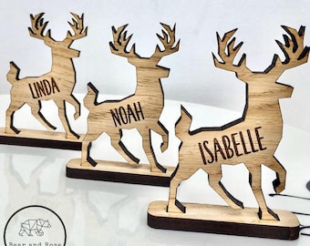 May include: Three wooden reindeer place card holders with the names Linda, Noah, and Isabelle engraved on them.