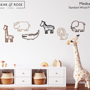 K&ouml;nnte beinhalten: Holz-Wanddekorationen mit Tieren: Giraffe, Nashorn, Zebra, Krokodil, L&ouml;we und Elefant. Die Giraffe ist gefleckt, die anderen Tiere sind aus Holz. Der Text "BEAR & ROSE YORK" ist sichtbar. Mittlere Gr&ouml;&szlig;e.