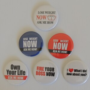 May include: Six round button badges with motivational slogans. The badges are white, red, blue, and black with white text. The slogans include "Lose Weight Now Ask Me How", "Own Your Life Ask Me How", "Fire Your Boss Now", and "I What I Do! How About You?"