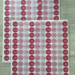 May include: Two sheets of pink and magenta weight loss stickers. Each sticker is a circle with a weight loss amount in pounds, ranging from -0.5lb to -5lb.