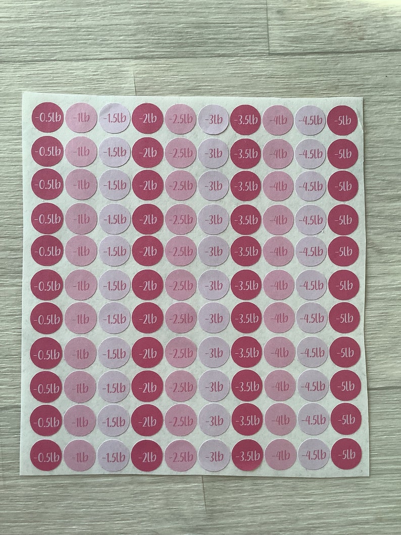 May include: A sheet of pink and light pink circular stickers. Each sticker has a weight measurement in pounds, ranging from -0.5lb to -5lb. The stickers are arranged in a grid pattern on a white background.
