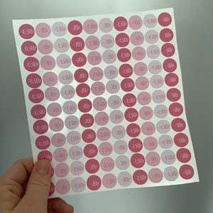 May include: Sheet of pink and magenta weight loss stickers. Each sticker is a circle with a weight loss amount in pounds, ranging from -0.5lb to -5lb. The stickers are held by a hand.