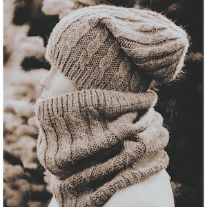 May include: A knitted hat and cowl set in a neutral, earthy tone. The hat features a cable knit design, and the cowl is a thick, warm accessory. The set is designed for cold weather and provides warmth and style.