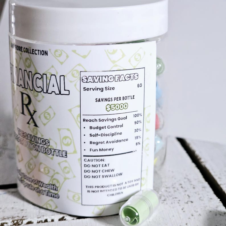 May include: A white plastic jar with a green and white label that reads "Saving Facts" and "&pound;5000". The label also includes a list of savings goals and percentages. The jar is filled with small, colourful pills.