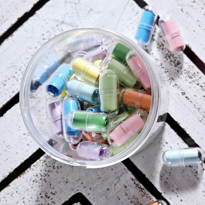 May include: A clear plastic jar filled with colourful capsules containing rolled up paper notes. The capsules are in various shades of blue, green, yellow, pink, and purple.