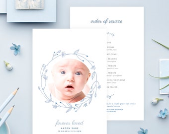 Op de afbeelding: Een blauwe en witte kaart met een bloemenkrans rond een foto van een babyjongen. De tekst "forever loved" staat onder de foto, gevolgd door de naam van de baby, "Aaden Sage", en de data "10.08.2018-11.15.2018".